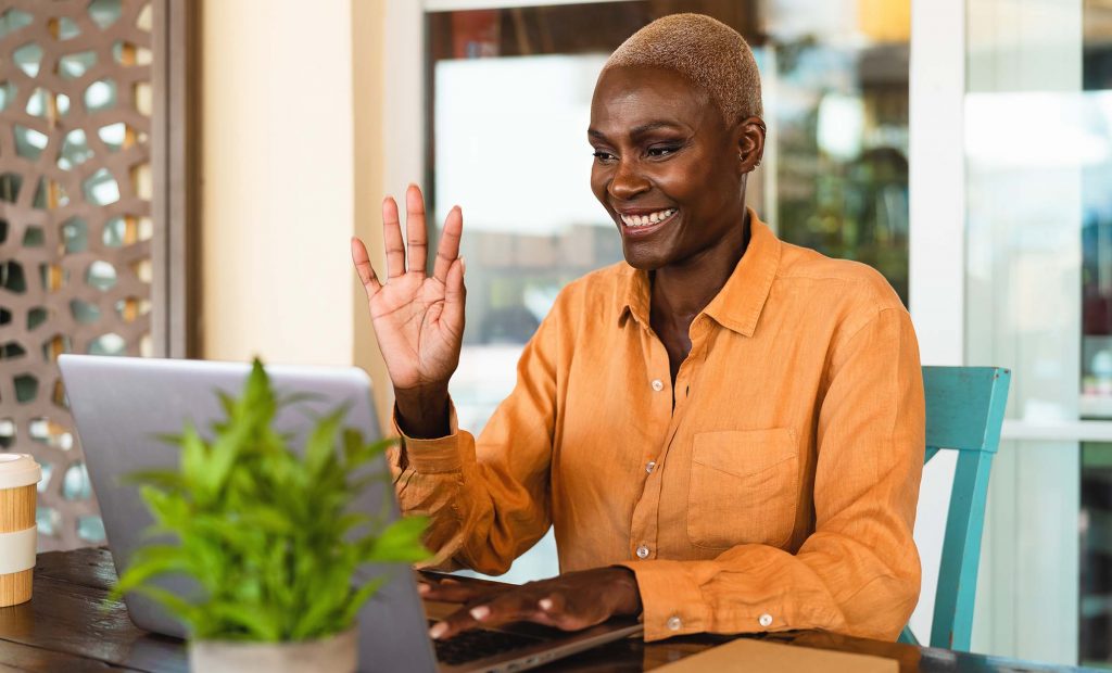 Smiling Black Woman Waving to Laptop