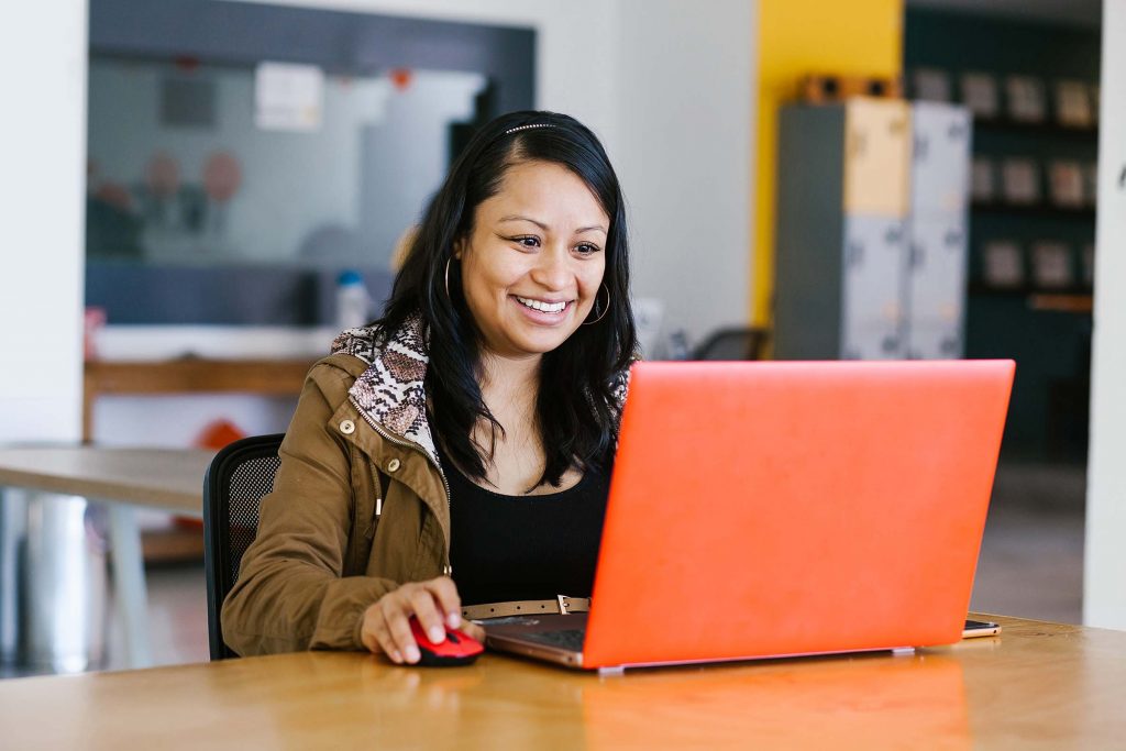 Smiling Latinx Woman Using Laptop