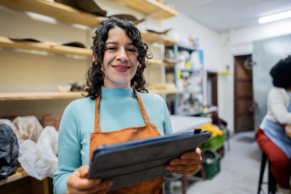 Portrait of a young saleswoman using digital tablet at ceramics workshop