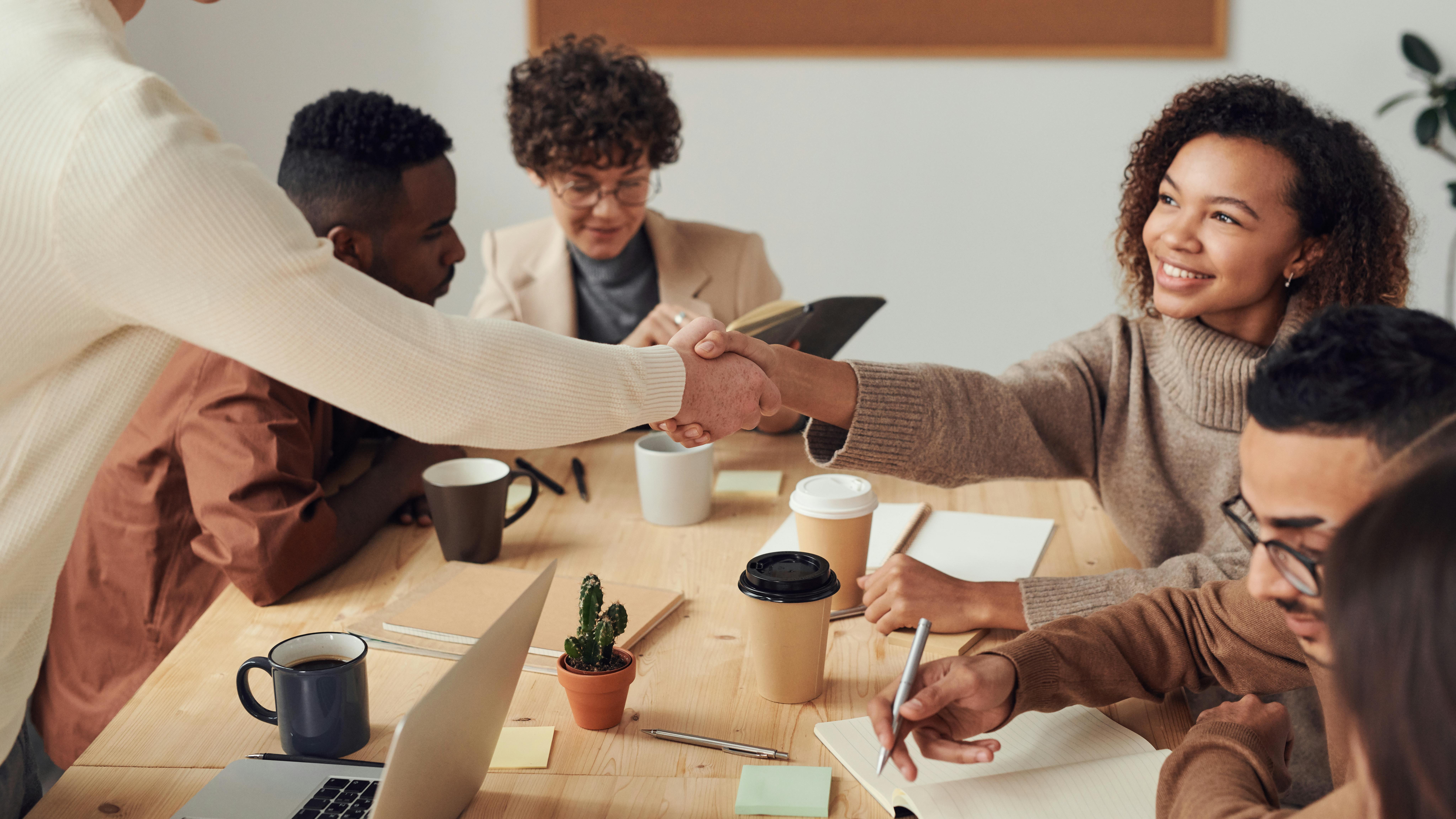 Group of diverse entrepreneurs meeting around a table, sharing ideas and collaborating in a bright workspace.”
